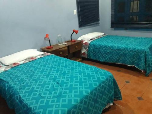 a room with two beds and a table with a night stand at Villa La Giralda - Lakefront - Pool - View - Relaxation Haven in Masaya