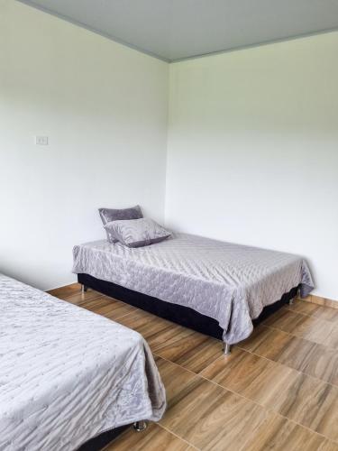 a bedroom with two beds and a wooden floor at Tumbaga Hostal in Quimbaya