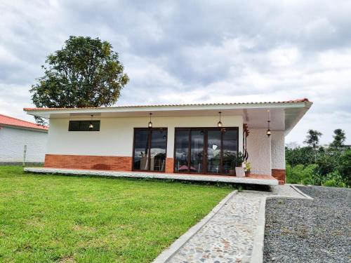 a small house with a green lawn in front of it at Tumbaga Hostal in Quimbaya