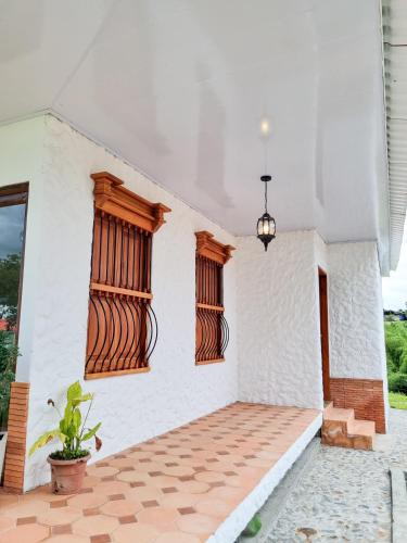 a house with white walls and wooden windows at Tumbaga Hostal in Quimbaya