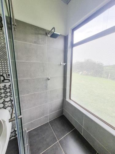 a bathroom with a shower and a window at Tumbaga Hostal in Quimbaya
