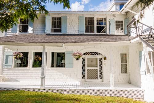 a white house with a porch with flowers on it at Auberge Les Sources in La Malbaie