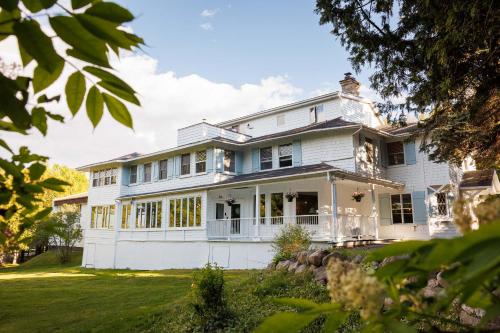 a large white house with a lawn at Auberge Les Sources in La Malbaie