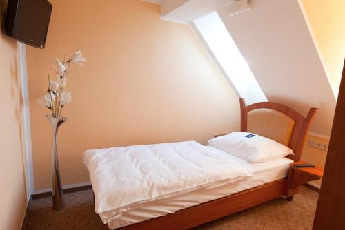 a bedroom with a bed with a vase of flowers at Aristo Hotel in Filderstadt