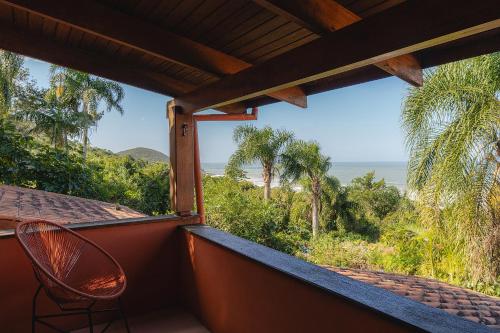 a room with a balcony with a view of the ocean at Pousada Villa Agrifoglio in Praia do Rosa
