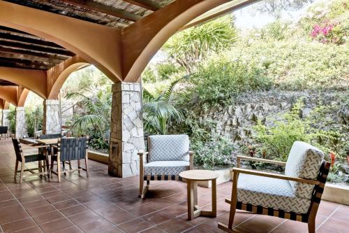 a patio with chairs and tables and a stone wall at Veridia Resort Sardinia, a member of Radisson Individuals in Chia