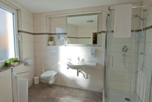 a bathroom with a toilet and a sink and a shower at Aristo Hotel in Filderstadt