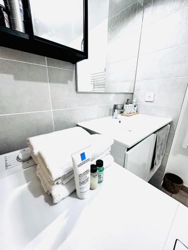 La salle de bains blanche est pourvue d'un lavabo et d'une serviette. dans l'établissement Superbe Apprt GARE DE VERT GALANT AEROPORT CHARLE DE GAULE, à Villepinte