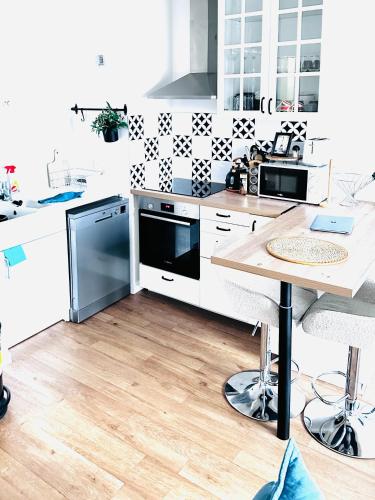 une cuisine avec comptoirs blancs et table en bois dans l'établissement Superbe Apprt GARE DE VERT GALANT AEROPORT CHARLE DE GAULE, à Villepinte
