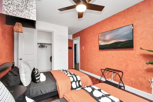 two beds in a room with an orange wall at ProlificSuites Escape - Stylish Spaces & Prime Location in Houston