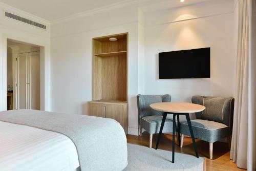 a hotel room with a bed and a table and chairs at Dolce CampoReal Lisboa in Turcifal
