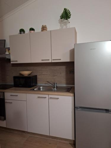 ブラシチにあるSplendidの白いキャビネット、シンク、冷蔵庫付きのキッチンが備わります。