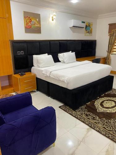 a bedroom with a large bed and two purple chairs at Kawruky Hotel Benin in Benin City