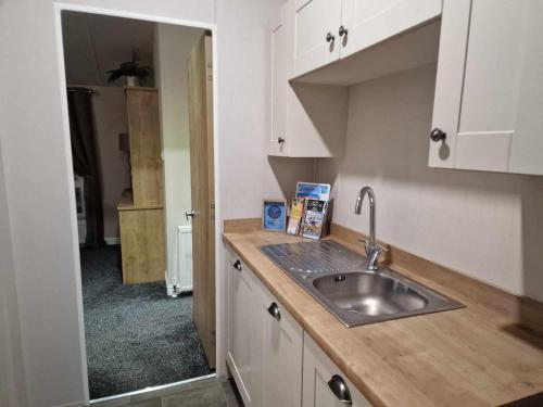 a kitchen with a sink and white cabinets at Sea Breeze, Vintage 90, Luxury 2 bed Lodge, Skegness, 2 friendly - East Coast Holidays in Winthorpe