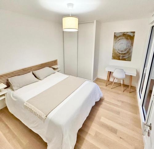 une chambre blanche avec un grand lit et un bureau dans l'établissement Nice flat Paris Clichy, à Clichy