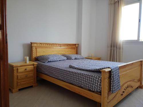 a bedroom with a wooden bed and a window at Résidence Maya in El Haouaria