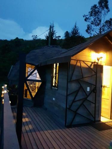 a small house with a wooden deck at night at Eco Lodge Glamping in Guatapé