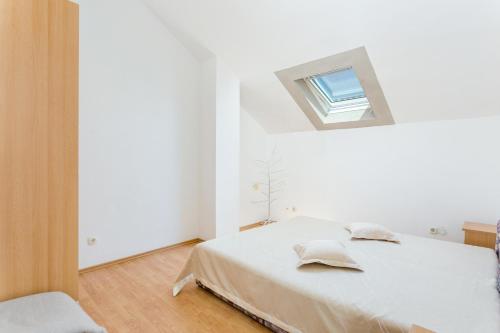 a white bedroom with a bed and a window at Apartments and rooms with parking space Supetar, Brac - 5658 in Supetar