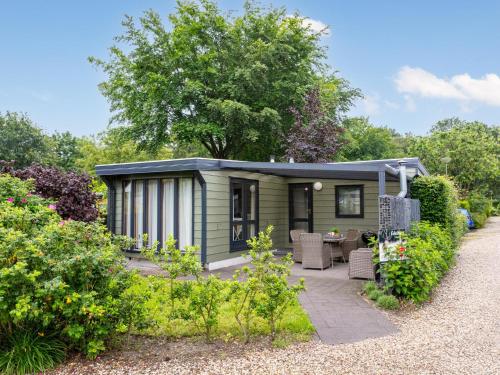 a green tiny house with a patio in a garden at Edelhert in Hulshorst