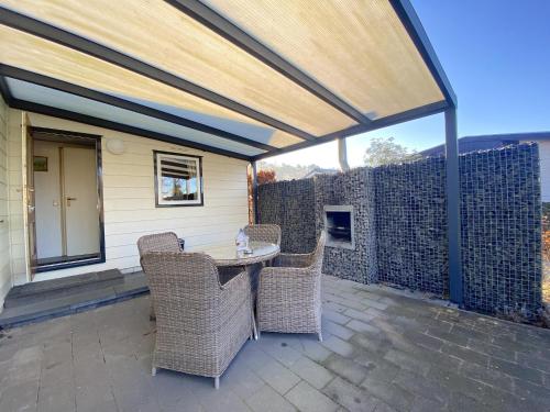 a patio with a table and wicker chairs at Edelhert in Hulshorst