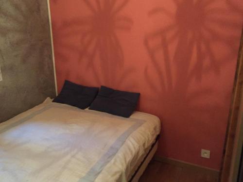 un petit lit avec deux oreillers sur un mur rouge dans l'établissement SOLEIL ET PLAGE A Sète, à Sète