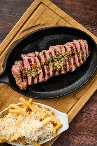 a piece of steak on a skillet with french fries at Ficus Sunset Suites in Monteverde Costa Rica