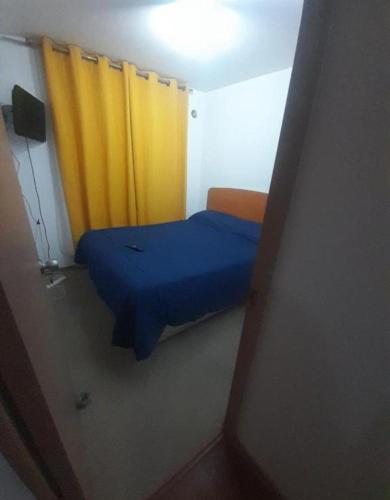a small room with a bed with a yellow curtain at Depto #102 Qta Valle in Vallenar