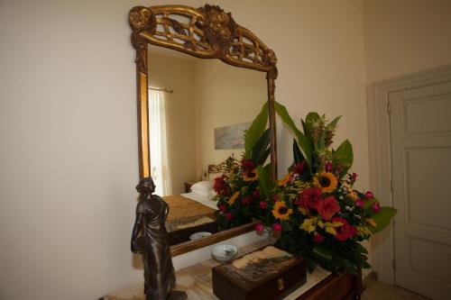 a bedroom with a mirror and a statue and flowers at B&B Nel Regno di Napoli in Naples