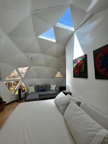 a bedroom with a large white bed and a couch at Eco Lodge Glamping in Guatapé