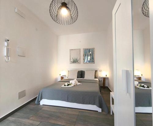 a white bedroom with a bed and two lamps at Casa vacanze green house in Terrasini