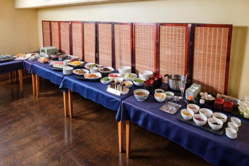 a long blue table with bowls of food on it at Miyazaki Mango Hotel in Miyazaki