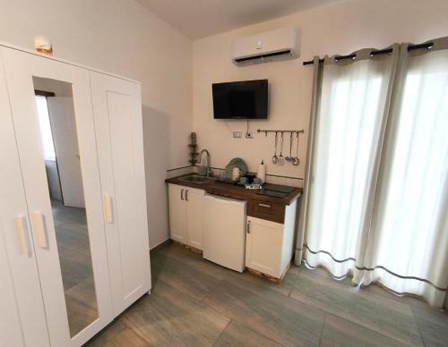 a room with a kitchen with a tv and a window at Casa vacanze green house in Terrasini