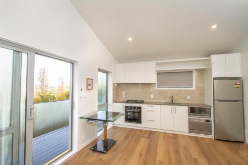 a kitchen with white cabinets and a large window at Basin View in Auckland