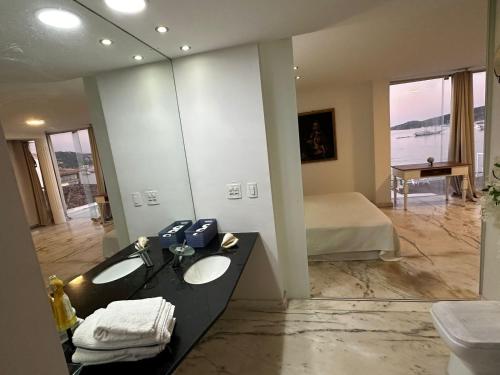 a bathroom with two sinks and a bed and a mirror at Villa Romana Búzios in Búzios