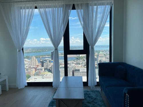 a living room with a blue couch and large windows at Sky Bridge Spectacular in Montréal