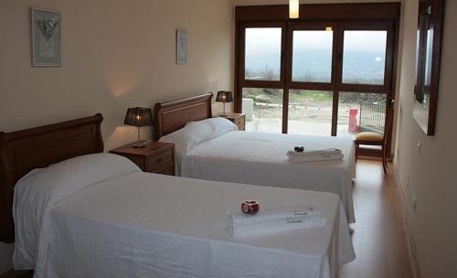 a hotel room with two beds and a window at Apartamentos La Covatilla in Neila de San Miguel