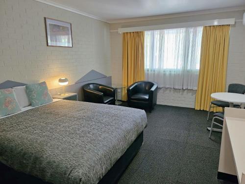a hotel room with a bed and a table and chairs at Central Deborah Motel in Bendigo
