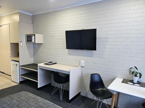 a room with a desk and a tv on a wall at Central Deborah Motel in Bendigo