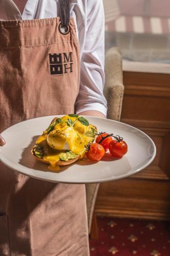a person holding a plate of food with tomatoes on it at Mountain Heritage Hotel in Katoomba