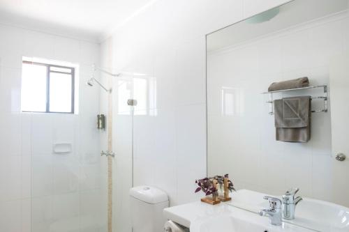 a white bathroom with a sink and a shower at Central Deborah Motel in Bendigo