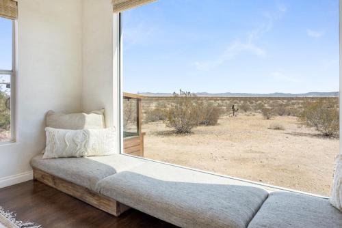 a living room with a couch and a large window at Desert Moon - Serene Desert Views & Design home in Joshua Tree
