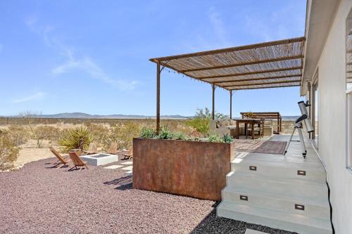 a patio with a wooden pergola and a table at Desert Moon - Serene Desert Views & Design home in Joshua Tree