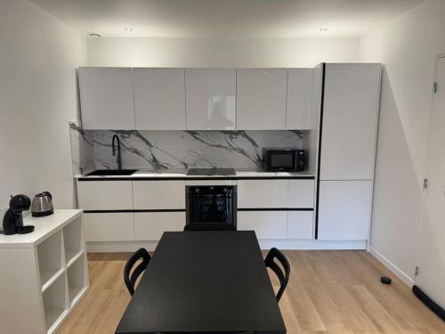 - une cuisine avec des placards blancs et une table noire dans l'établissement Appartement VII - Haut Standing, à Nilvange