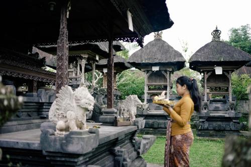 a woman standing in front of a building eating food at Homestay D'BANDEM in Penginyahan
