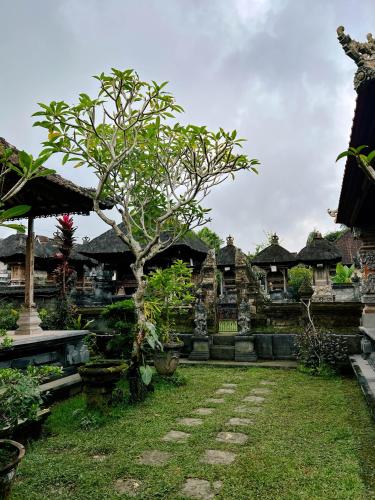 a garden with a tree in front of a building at Homestay D'BANDEM in Penginyahan