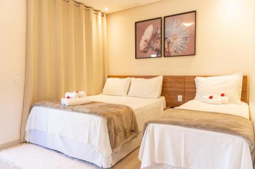 a bedroom with two beds with white sheets at Vila da Mata Chalés in Alto Paraíso de Goiás