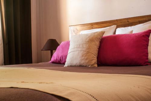 a bed with pink and white pillows on it at Couleur Café in Antsirabe