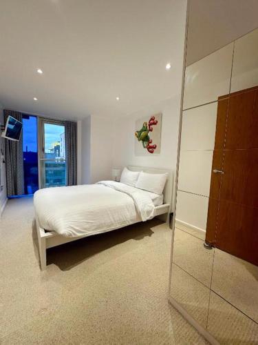 a white bedroom with a bed and a mirror at Canary Wharf - Luxury Apartments in London