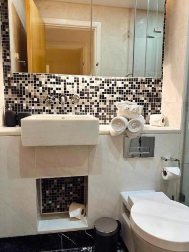 a bathroom with a sink and a toilet and a mirror at Canary Wharf - Luxury Apartments in London