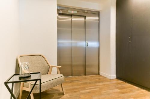 a room with a chair and a glass table and a elevator at Kyriad Crepy En Valois in Crépy-en-Valois